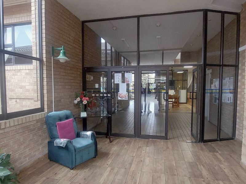 A bright and welcoming retirement village entrance area featuring exposed brick walls, tiled flooring, and large glass doors leading to the interior.