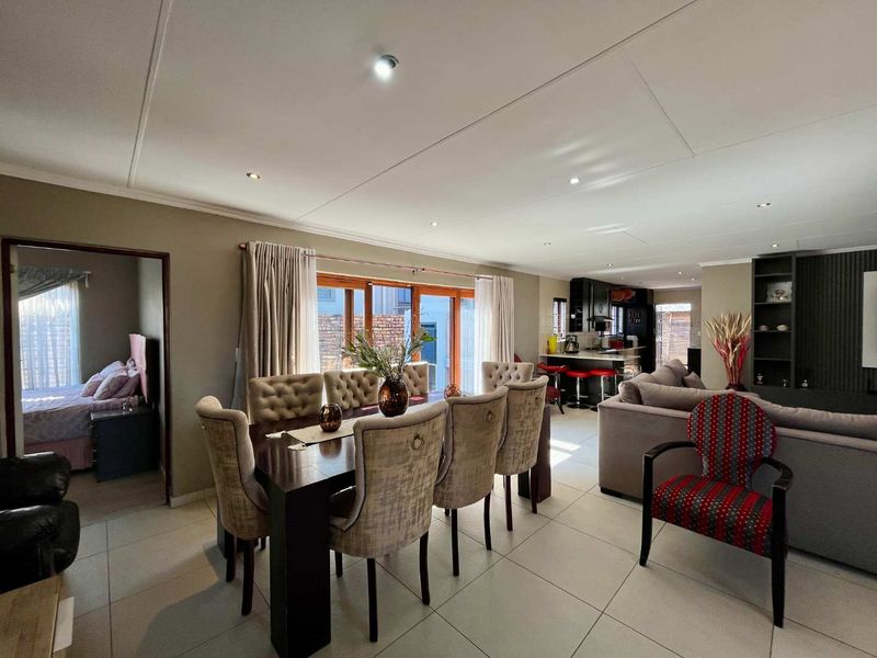 Spacious open-plan living and dining area featuring tiled floors, recessed lighting, and seamless flow to the kitchen and adjacent bedroom.