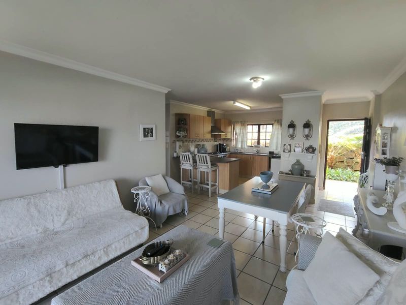 Open-plan living and dining area featuring tiled flooring, coved ceilings, and a functional kitchen with built-in cabinetry and a breakfast counter.