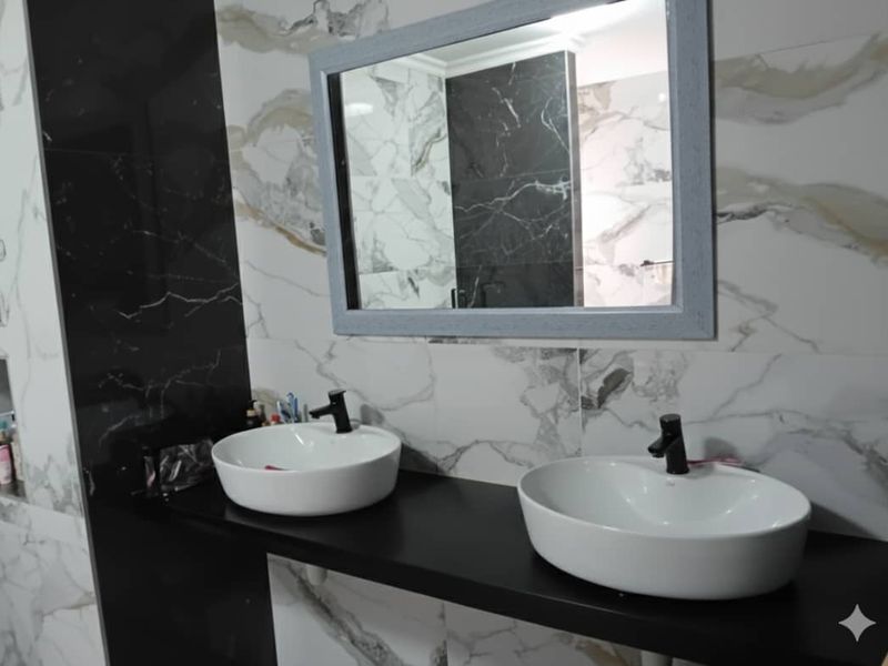 Modern bathroom featuring a double vanity with vessel sinks, black fixtures, and striking marble-effect wall tiling.