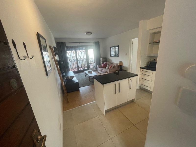 Open-plan living area featuring a kitchen island, built-in cabinetry, and direct access to a balcony through a sliding security gate.