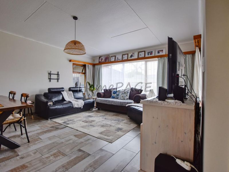 Open-plan living and dining area featuring tiled flooring, large windows for natural light, and a central pendant light fixture.