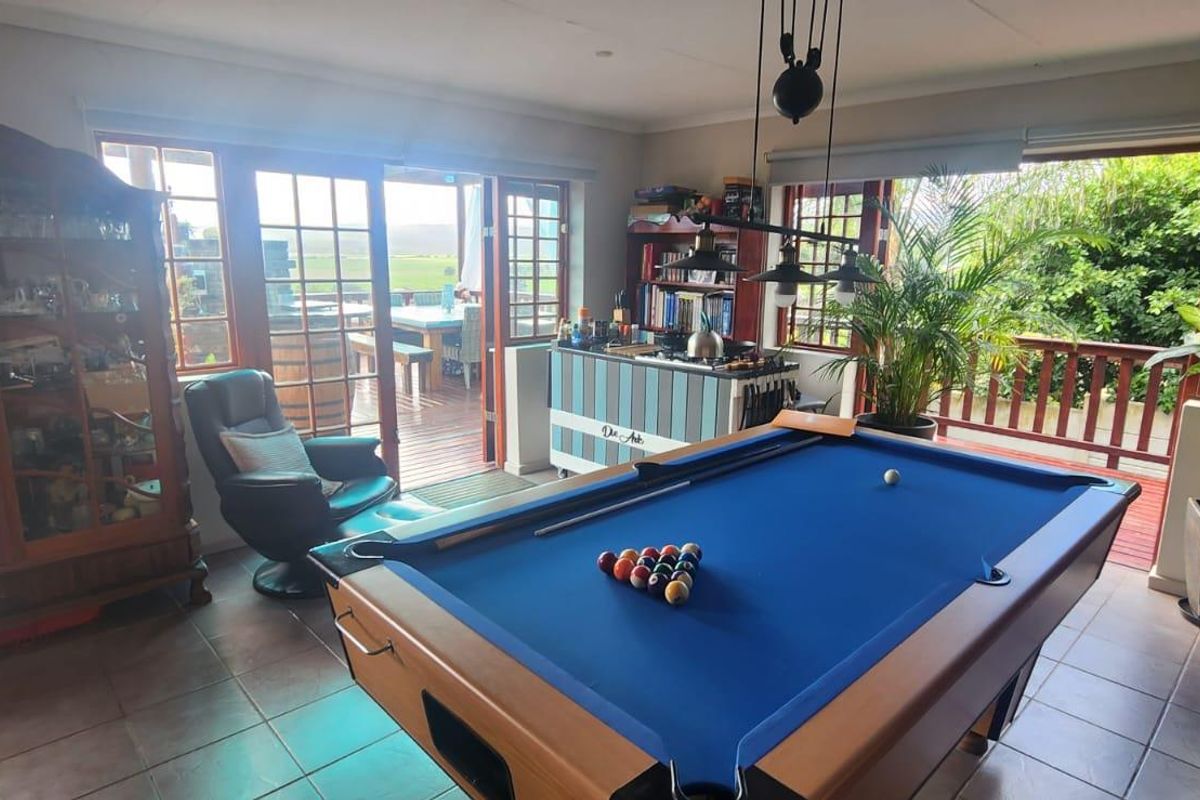 Spacious living area featuring tiled flooring, large wooden-framed glass doors providing access to an outdoor deck, and ample natural light.