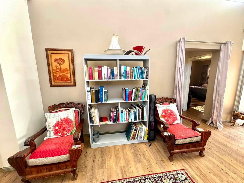 A living area featuring laminate flooring and an arched doorway leading to an adjacent room.