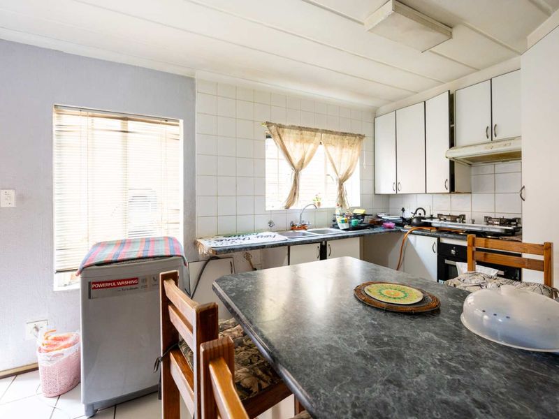 A functional kitchen featuring built-in cabinetry, a tiled backsplash, and integrated appliances, offering a practical layout with potential for modern updates.