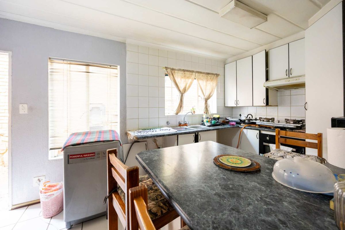 A functional kitchen featuring built-in cabinetry, a tiled backsplash, and integrated appliances, offering a practical layout with potential for modern updates.