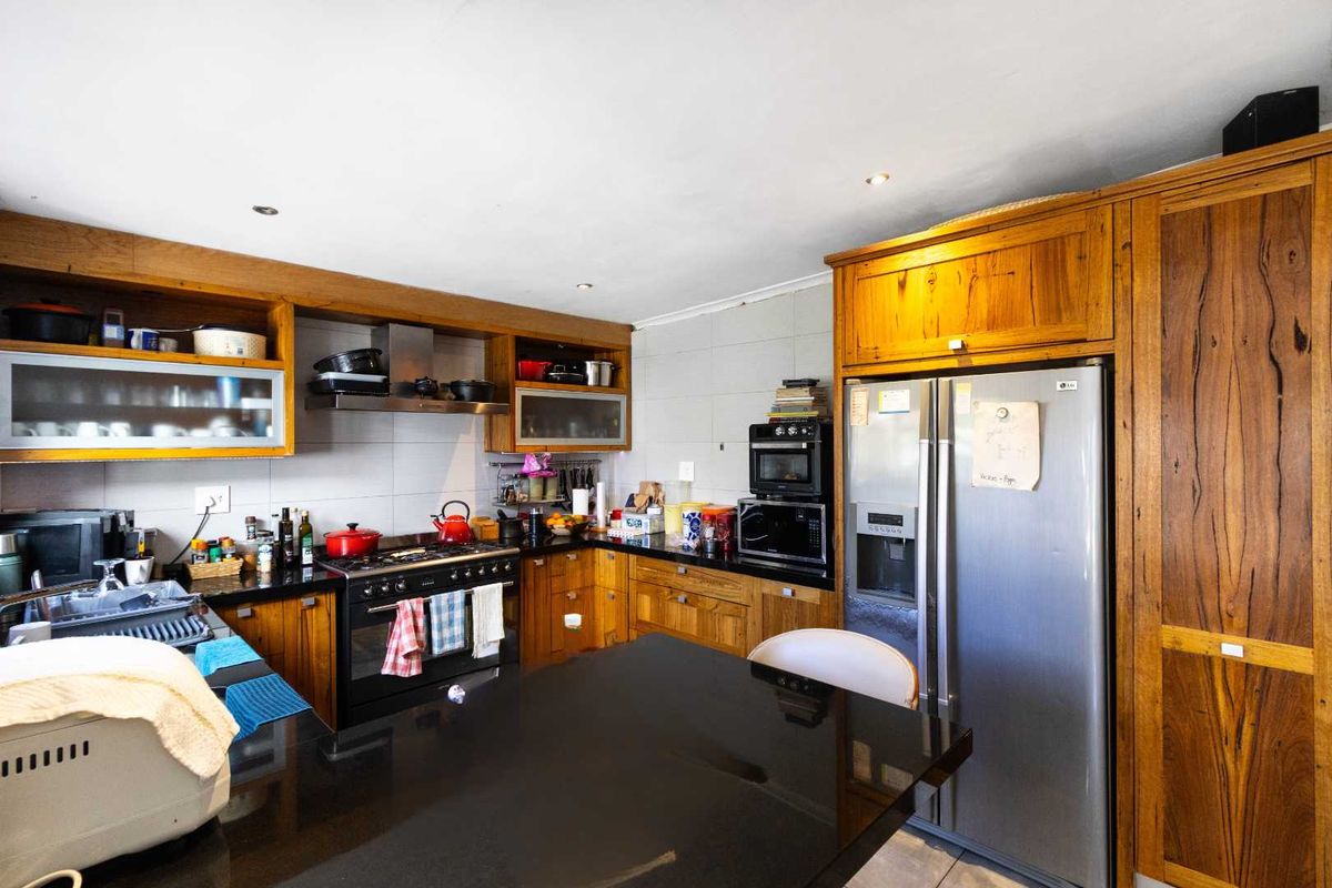 A functional kitchen featuring solid wood cabinetry, black granite countertops, a built-in oven, and a stainless steel extractor fan.