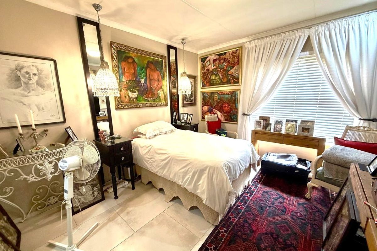 A cozy bedroom featuring tiled flooring, window blinds, and decorative ceiling lighting, offering a comfortable and well-maintained living space.