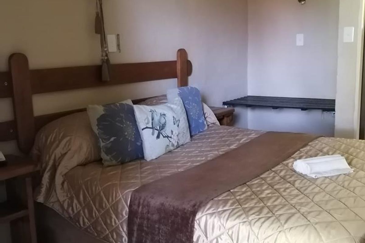 A bedroom featuring a built-in wooden headboard, wall-mounted lighting, and a fixed luggage rack.