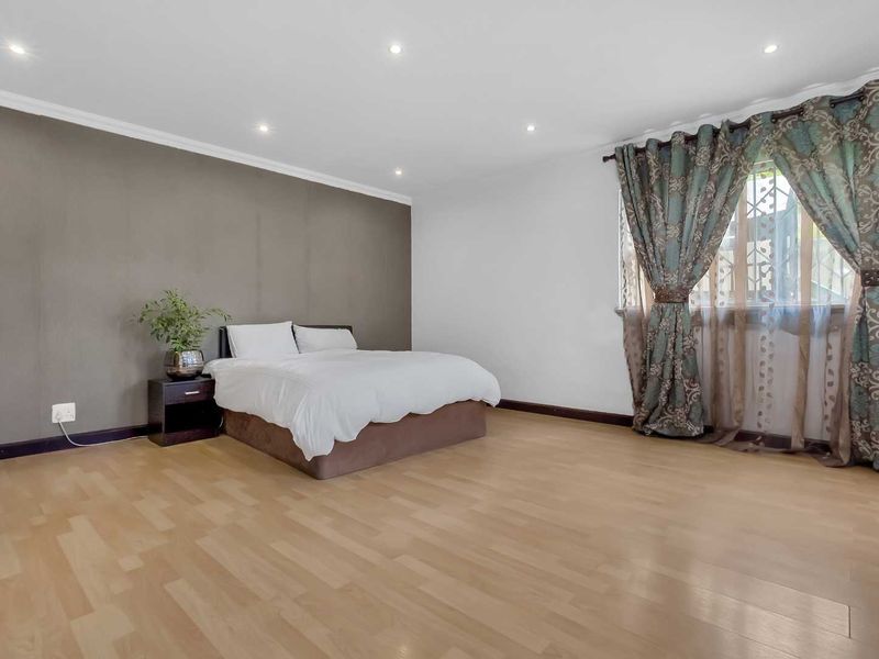 Spacious bedroom featuring neutral wall tones, recessed downlighting, and light-toned laminate flooring, offering a clean and versatile living space.