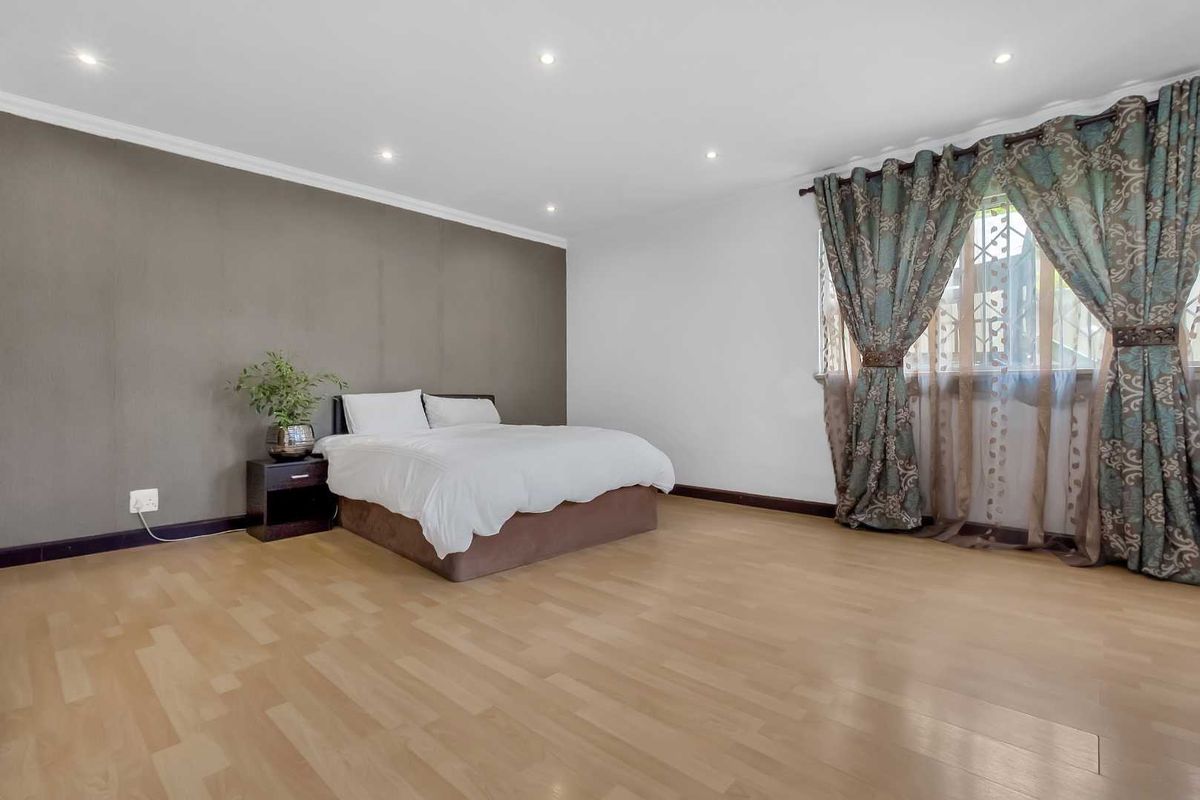 Spacious bedroom featuring neutral wall tones, recessed downlighting, and light-toned laminate flooring, offering a clean and versatile living space.