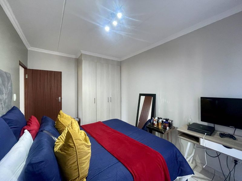 A well-maintained bedroom featuring neutral walls, built-in cupboards, and decorative ceiling cornicing, providing a clean and functional living space.