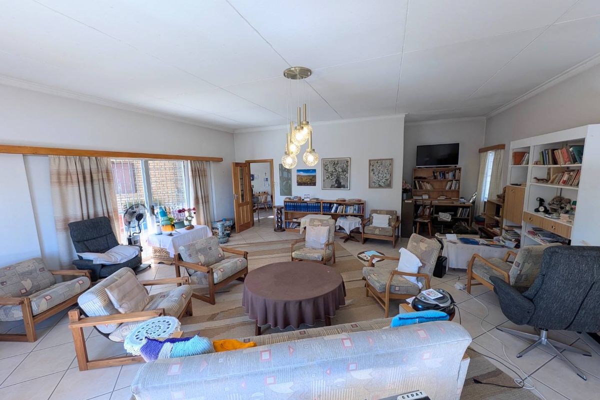 Spacious living room featuring tiled flooring, large sliding glass doors for natural light, and a central pendant light fixture.