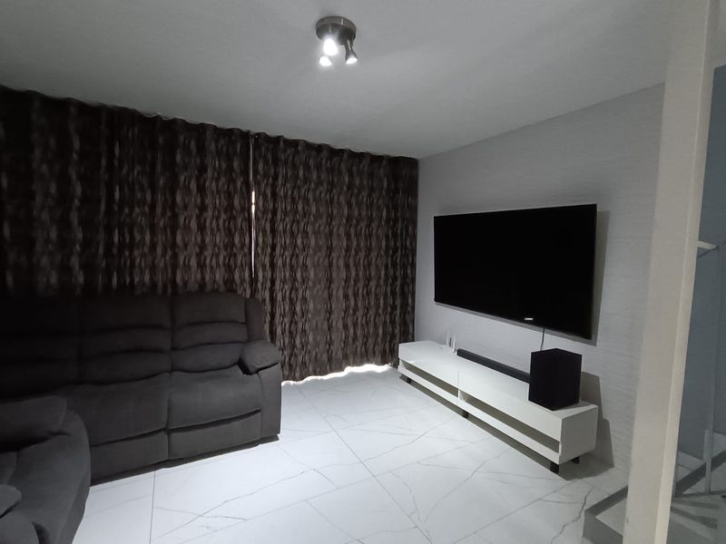 A modern living room featuring large format marble-look floor tiles, textured feature wall, and integrated ceiling lighting.