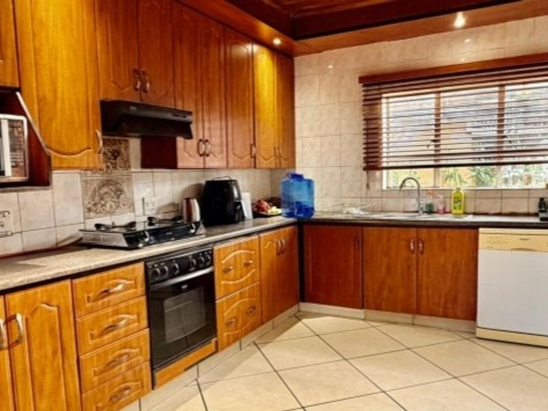 A functional kitchen featuring traditional wooden cabinetry, a built-in oven with gas hob, tiled backsplash, and tiled flooring with ample counter space.