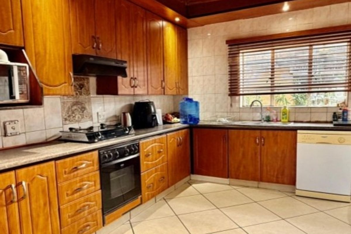A functional kitchen featuring traditional wooden cabinetry, a built-in oven with gas hob, tiled backsplash, and tiled flooring with ample counter space.