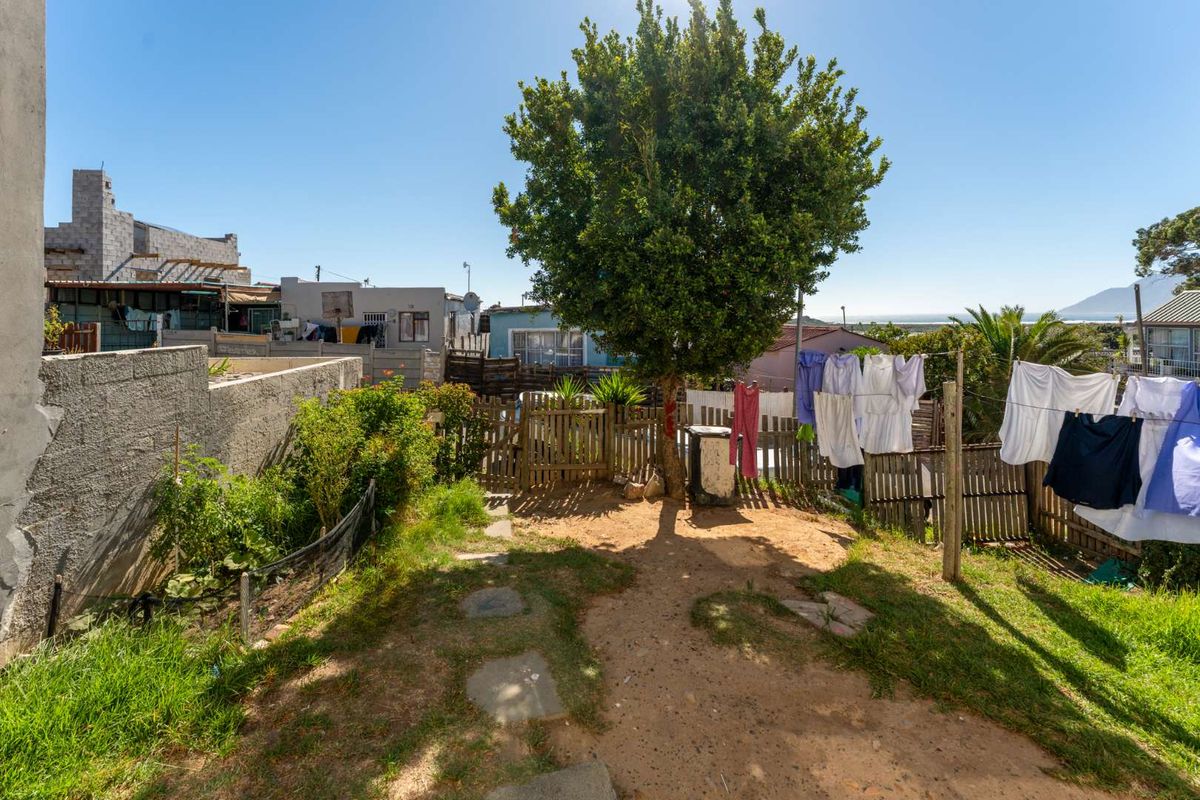 A rear garden area featuring a mature tree, grassed sections, and timber boundary fencing with views towards the surrounding neighborhood.