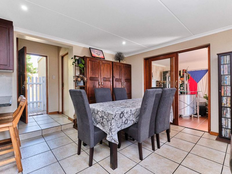Dining area featuring tiled flooring and recessed lighting, with direct access to an external entrance and an adjacent room through sliding glass doors.