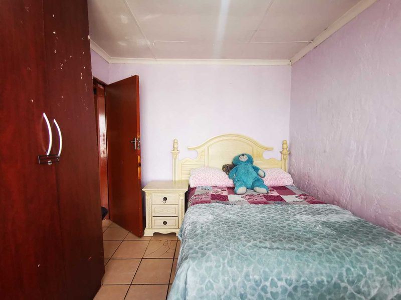 A compact bedroom featuring tiled flooring, a built-in wardrobe, and coved ceiling details, requiring cosmetic updates to improve the overall finish.
