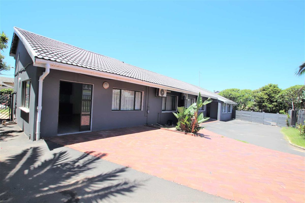 Rear exterior view of the house featuring a paved driveway, tiled roof, and external air conditioning unit.