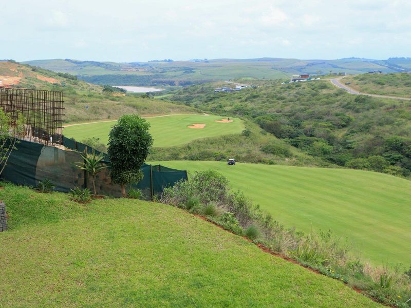 Elevated view overlooking a golf course and rolling hills, featuring a landscaped lawn and a gabion retaining wall structure.