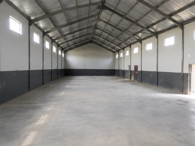 Spacious industrial warehouse unit featuring a high-clearance steel portal frame, durable concrete flooring, and ample natural light from high-level windows.