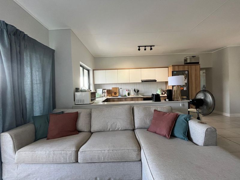 Open-plan living area featuring a functional kitchen with built-in cabinetry, a breakfast counter, and tiled flooring throughout.