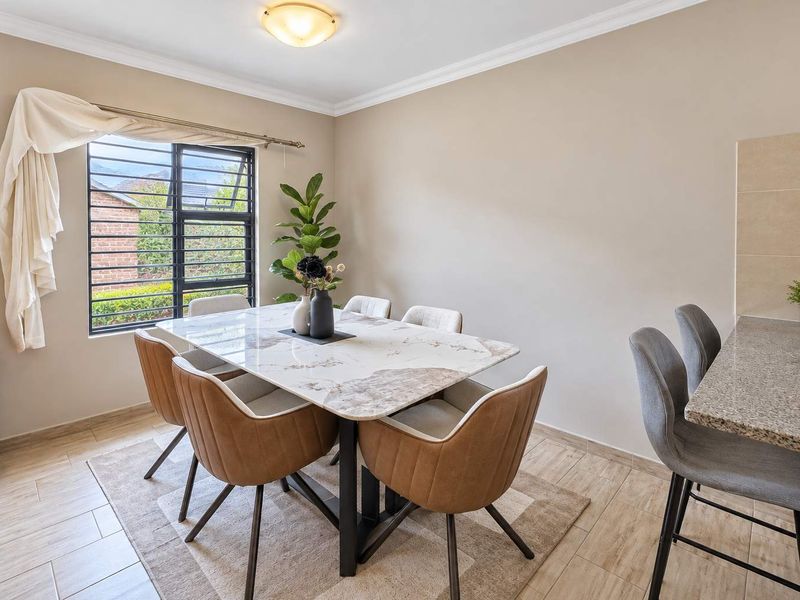 Open plan dining area featuring tiled flooring, a granite breakfast bar, and a window with security bars, creating a functional and well-lit living space.