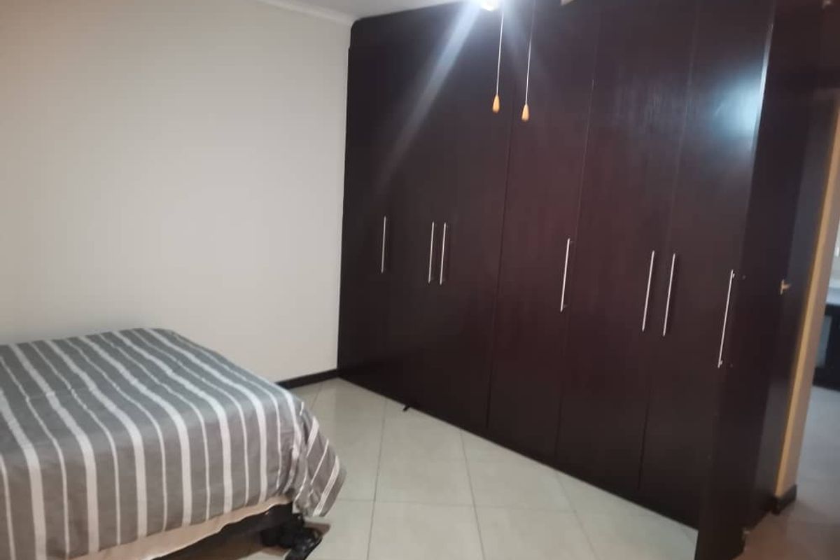 A bedroom featuring extensive dark wood built-in cabinetry and tiled flooring.