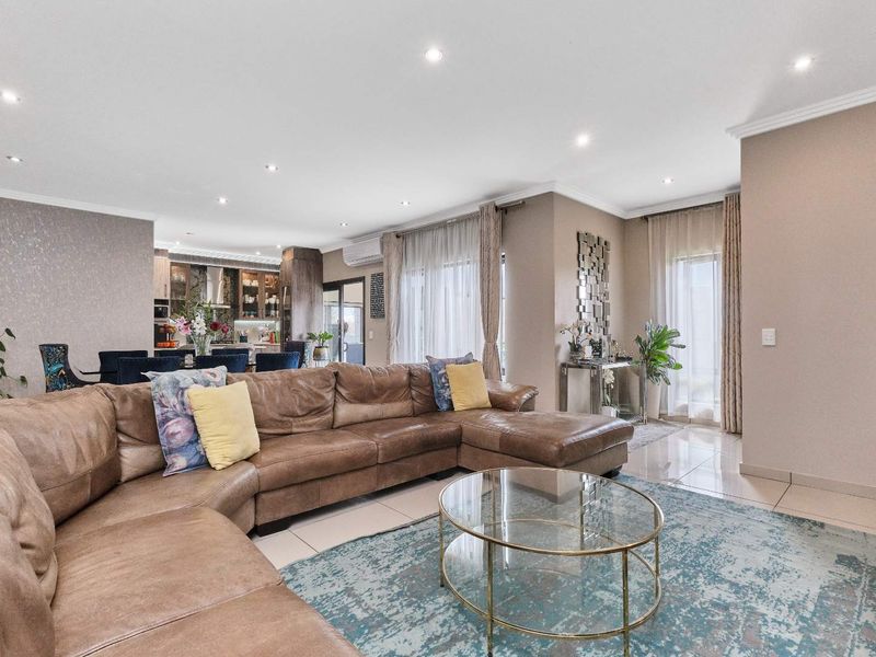 Spacious open-plan living and dining area featuring modern porcelain tiles, recessed lighting, and seamless flow to the kitchen and outdoor access.