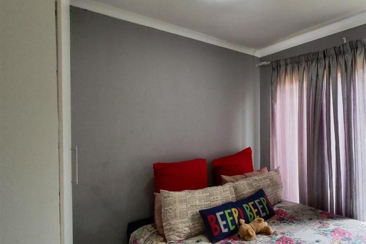 A bedroom featuring built-in cupboards and a window with curtain tracks.
