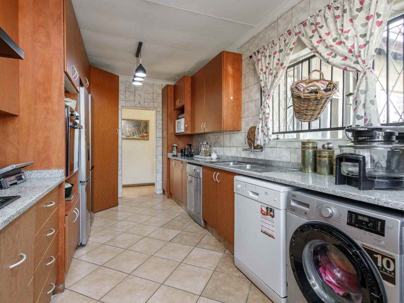 A functional kitchen featuring wooden cabinetry, granite countertops, tiled flooring, and integrated appliance spaces, offering a practical layout for daily use.