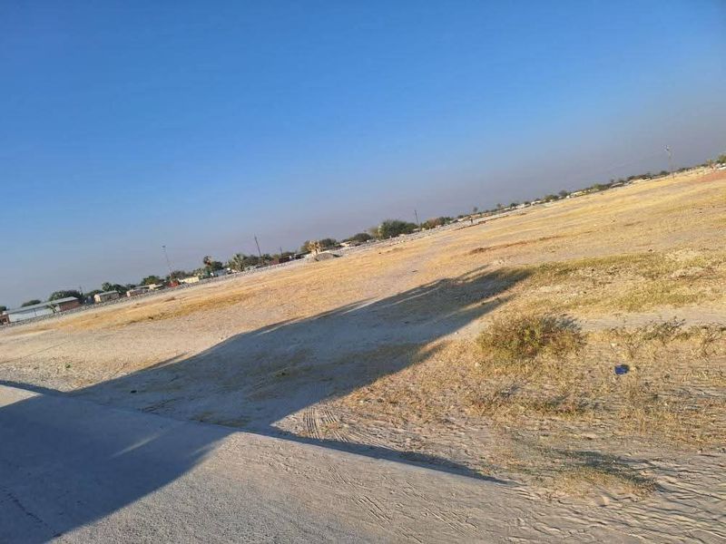A wide-angle view of a vacant residential plot of land, featuring open space and natural ground cover.