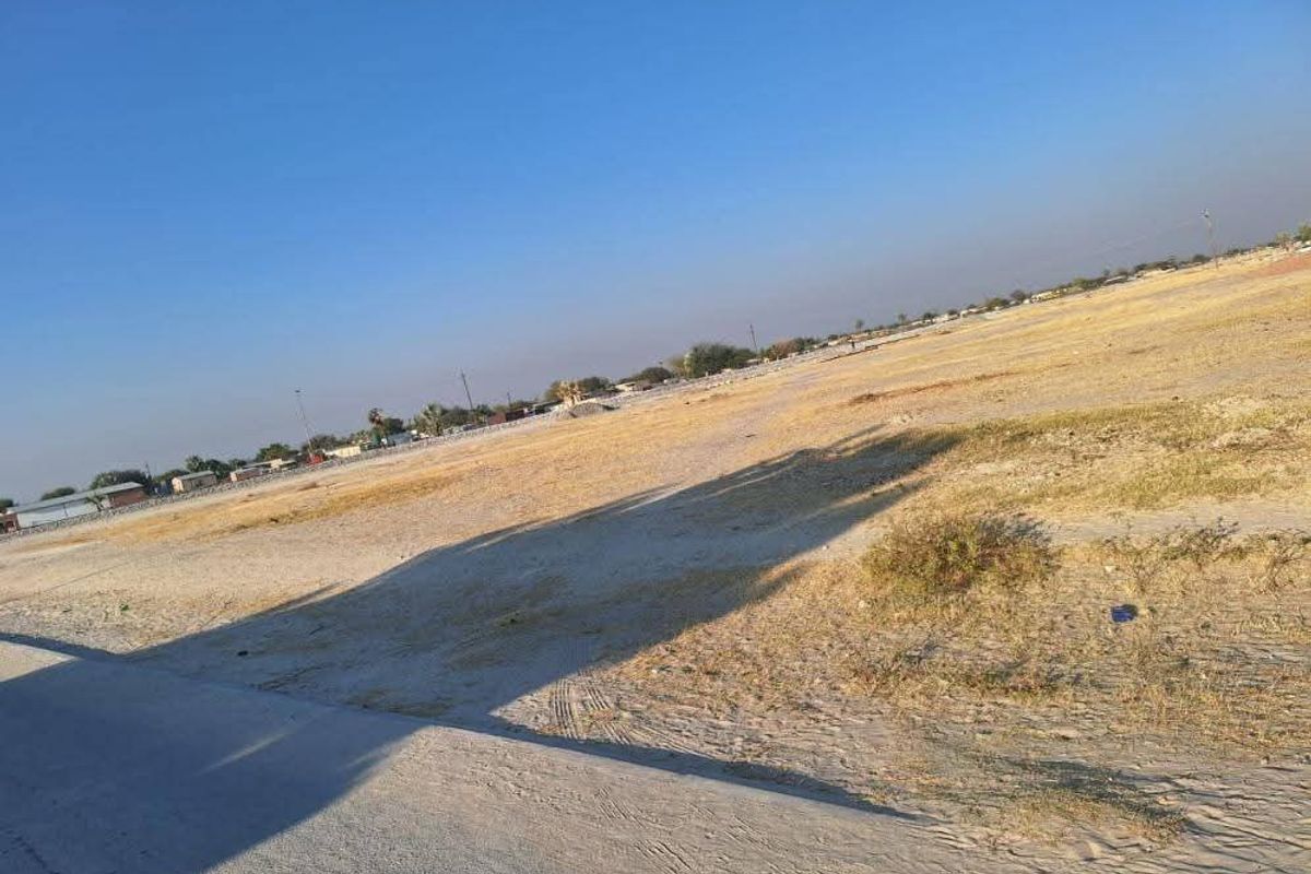 A wide-angle view of a vacant residential plot of land, featuring open space and natural ground cover.