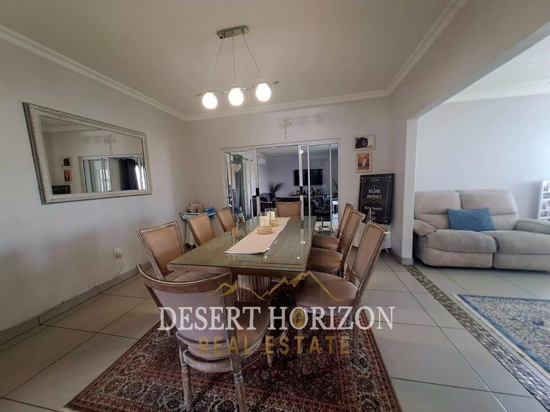 A well-lit dining room featuring tiled flooring, cove ceiling details, and sliding glass doors that provide a seamless transition to the adjacent living area.