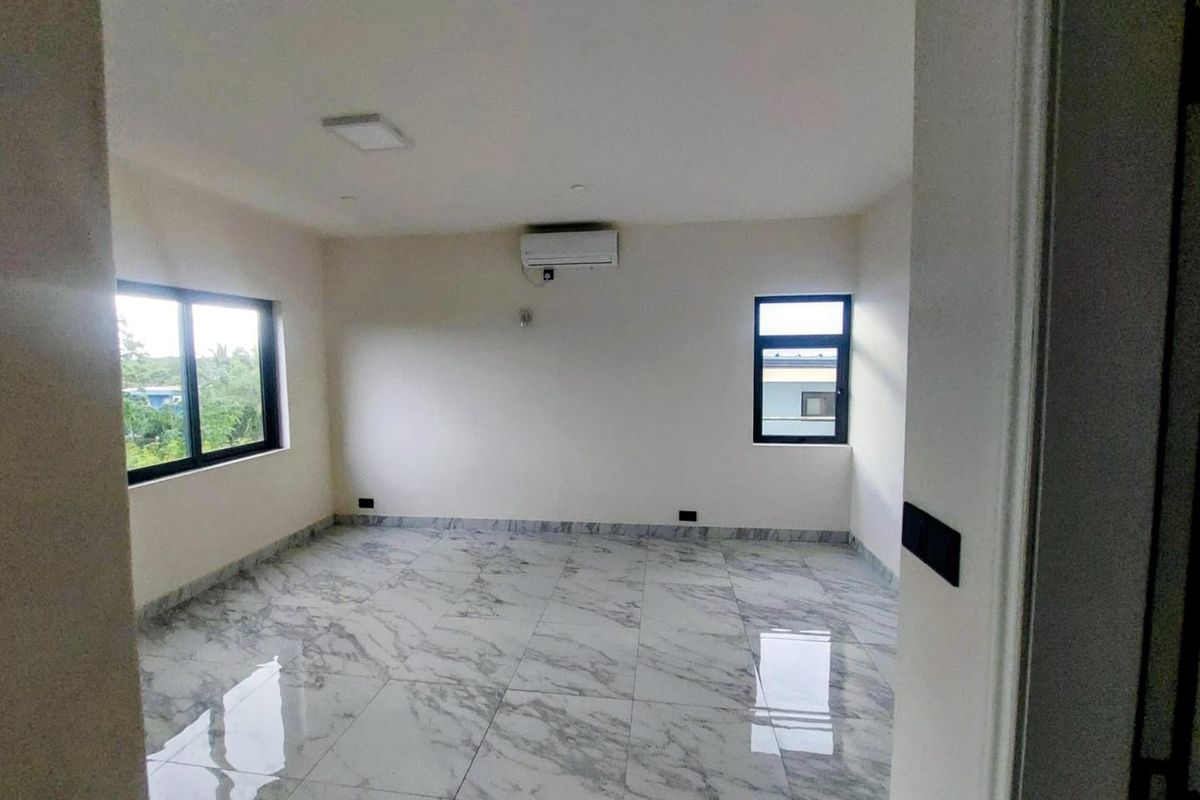 A bright, empty bedroom featuring polished marble-look floor tiles, modern black-framed windows, and a wall-mounted air conditioning unit.