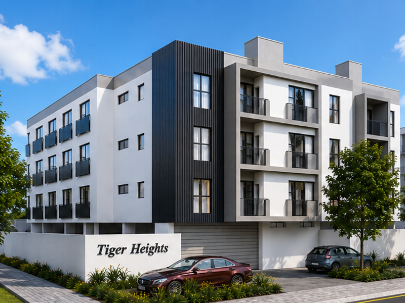 Modern multi-story apartment building facade featuring contemporary architectural design, private balconies with metal railings, and a paved ground-level parking area.