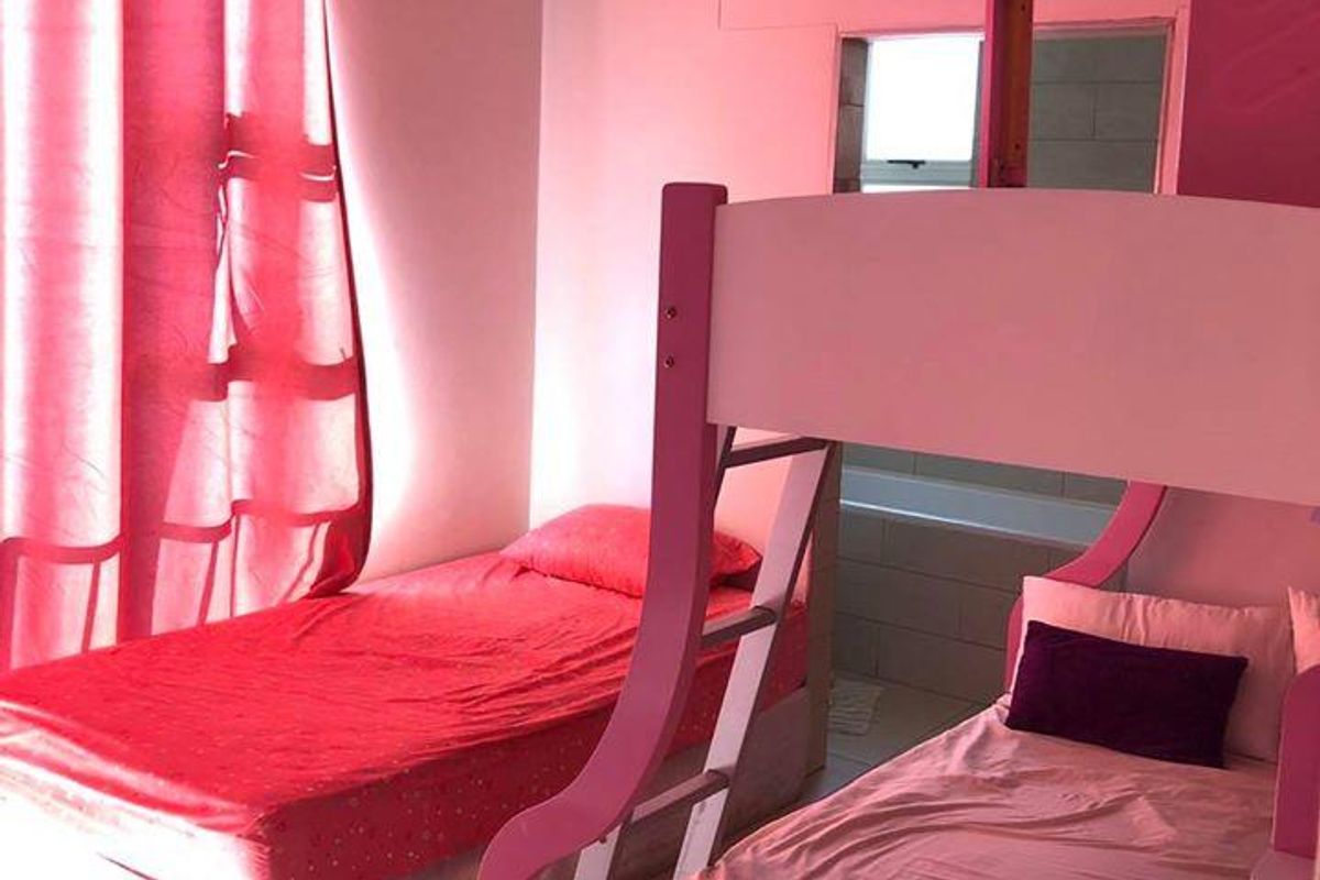 A bedroom featuring tiled flooring and a ceiling-mounted light fixture, with an adjacent view into a bathroom area.