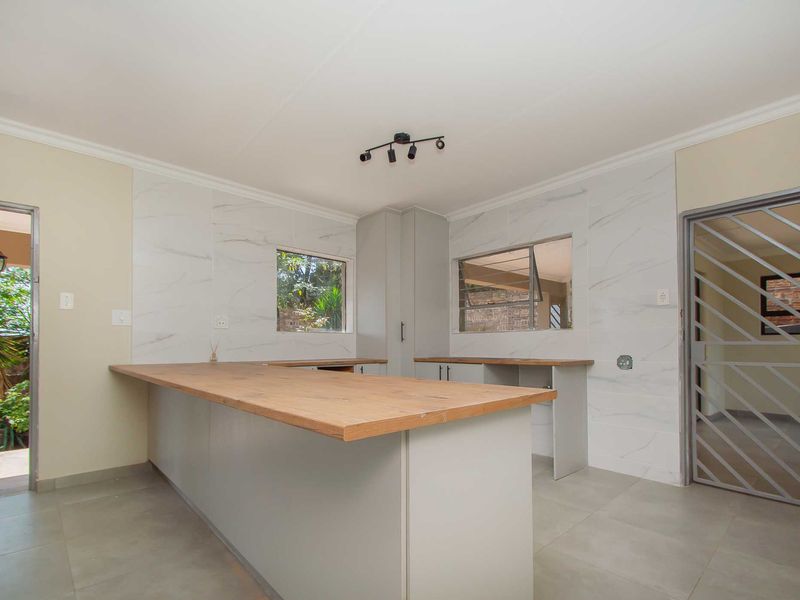 Modern kitchen featuring marble-look wall tiles, wooden countertops, and ample cabinetry, offering a clean and functional space ready for final finishing touches.