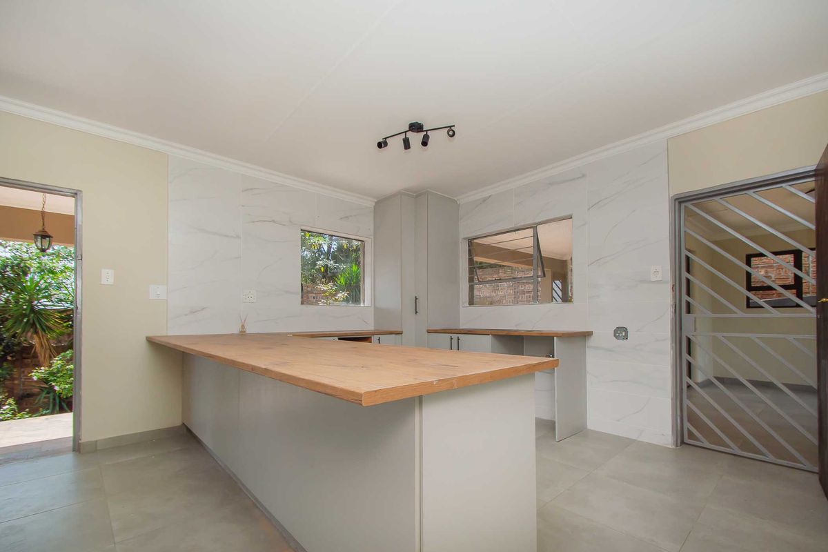 Modern kitchen featuring marble-look wall tiles, wooden countertops, and ample cabinetry, offering a clean and functional space ready for final finishing touches.