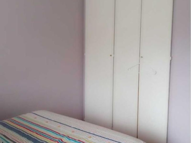 A bedroom featuring a built-in wardrobe with white doors and neutral wall finishes.