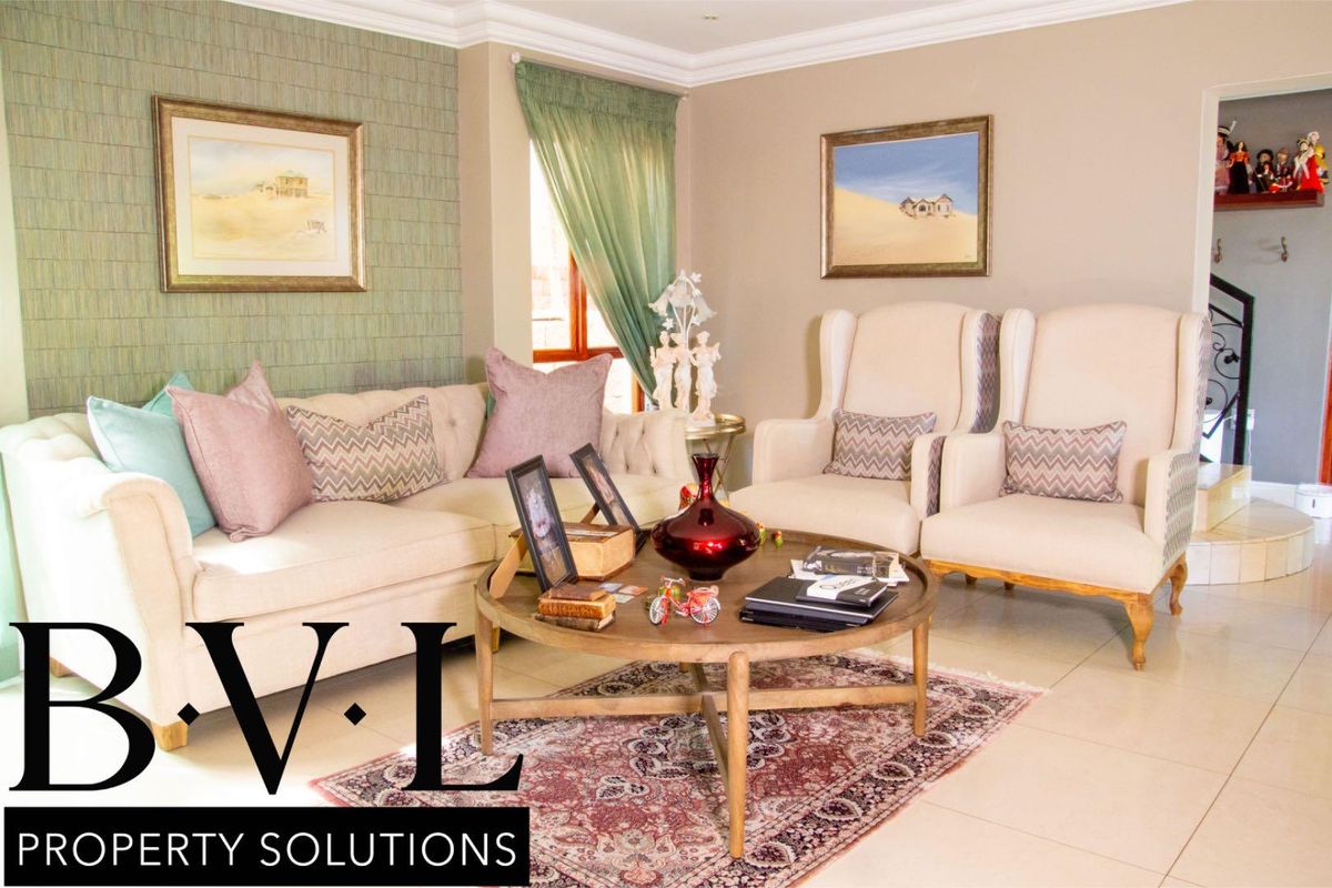 A well-maintained living room featuring tiled flooring, decorative wallpaper accent wall, and crown molding.