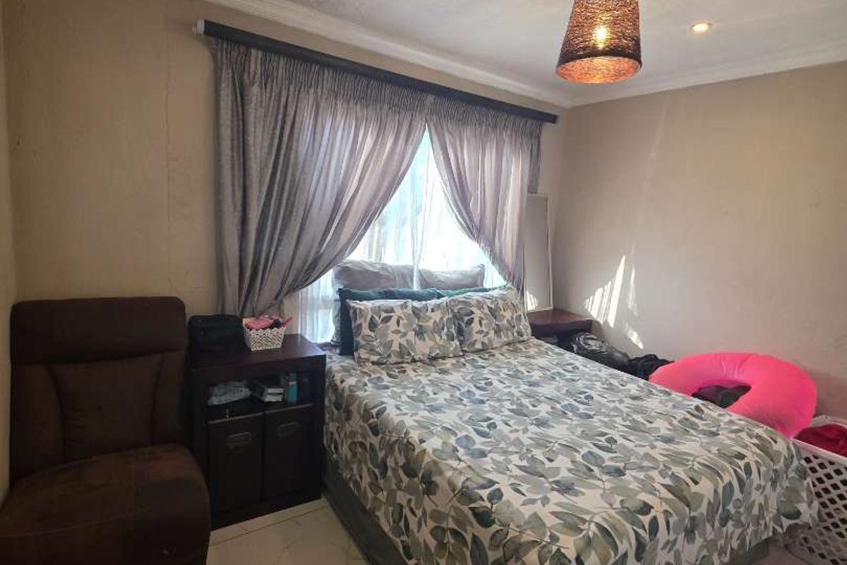 A bedroom featuring large format floor tiles, recessed downlighting, and a central pendant light fixture.