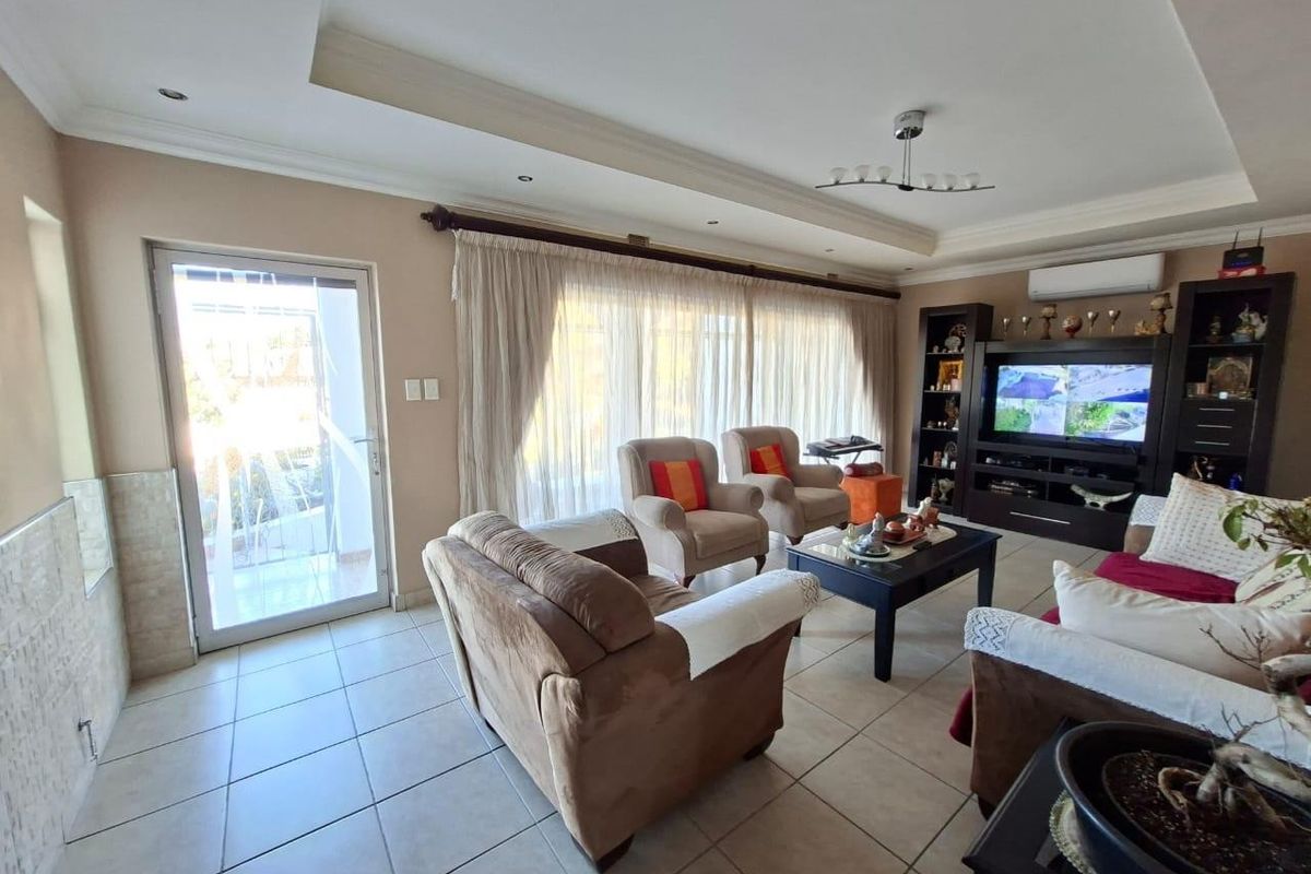 A comfortable living room featuring tiled flooring, a recessed ceiling, a built-in media unit, and direct access to an outdoor area via a sliding door.