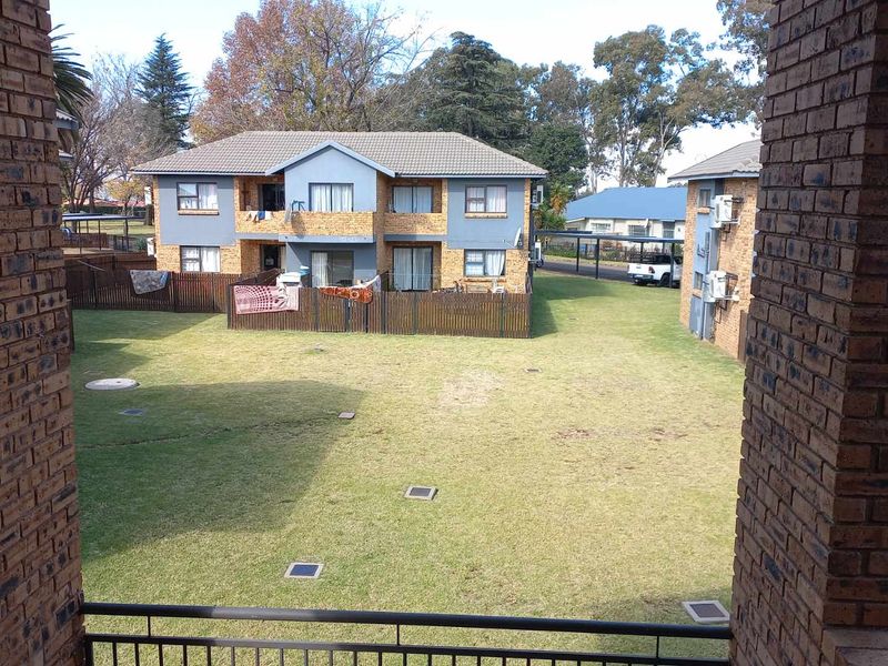 Elevated view overlooking a communal garden area between townhouse blocks, featuring brick construction and established lawn.