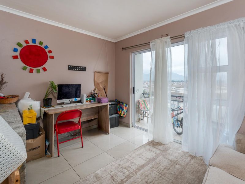 A living area featuring tiled flooring and a large sliding glass door providing access to a balcony with exterior views.