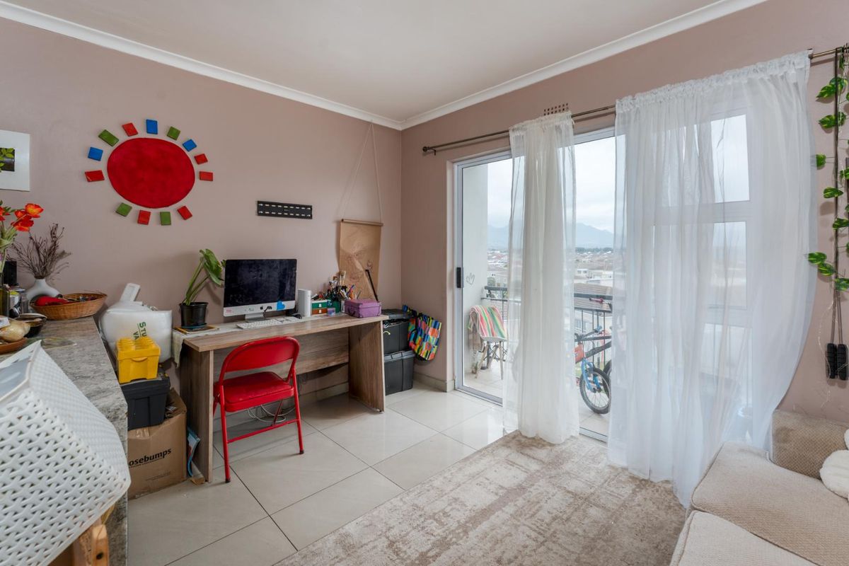 A living area featuring tiled flooring and a large sliding glass door providing access to a balcony with exterior views.