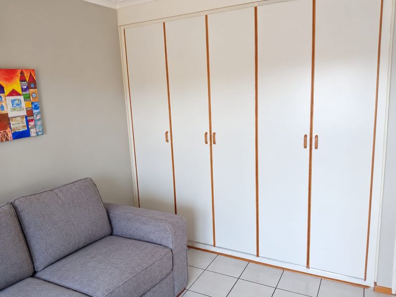 A bedroom featuring white built-in cupboards with wooden trim and tiled flooring.