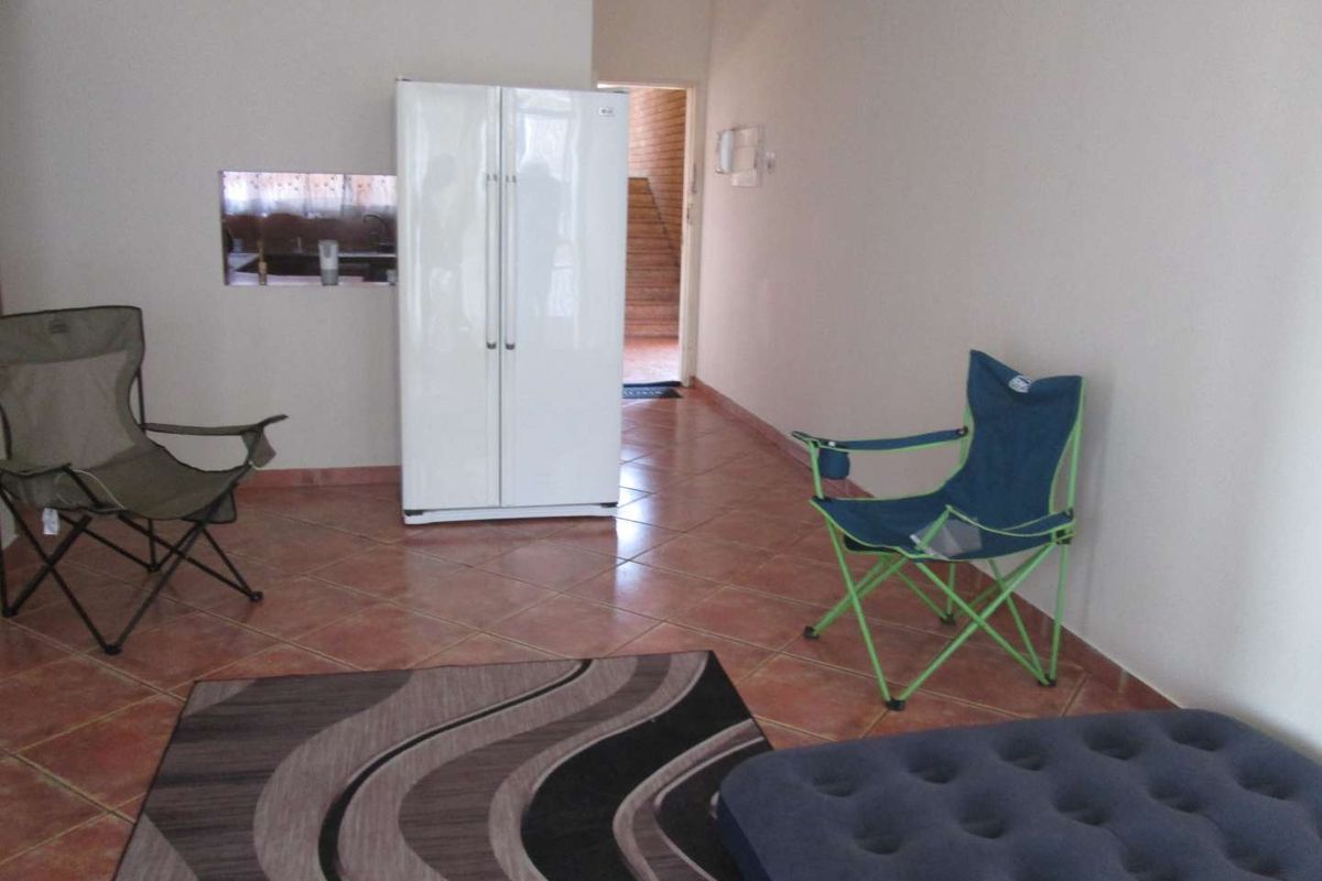 An open-plan living area featuring tiled flooring and a convenient pass-through window connecting to the kitchen space.