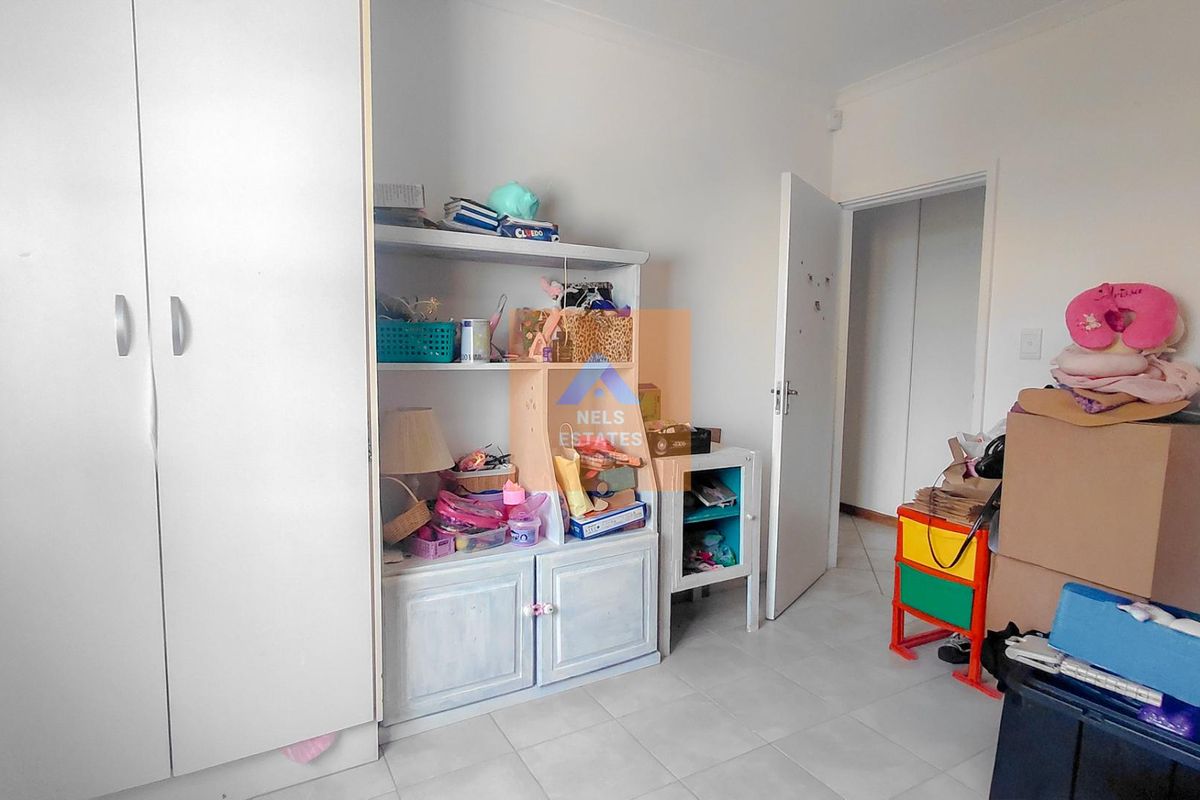A bedroom featuring tiled flooring and a built-in wardrobe, offering a functional space ready for personalization.